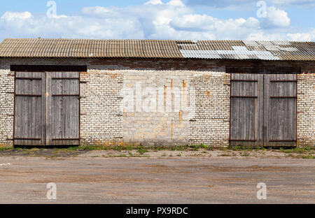 Ancien entrepôt de brique avec de grandes portes fermées, ciel bleu Banque D'Images