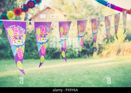 Décoration de fête d'anniversaire. Drapeaux de parti coloré avec gâteau d'anniversaire, ballons et partie de texte, le temps suspendu à la corde dans le jardin. Banque D'Images