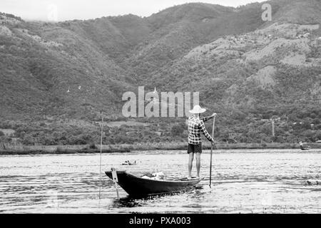 Les jeunes pêcheurs birmans portant une chemise à carreaux de retour à la maison après la pêche, debout sur le bord d'un mince voile de haut, l'aviron, le lac Inle Banque D'Images