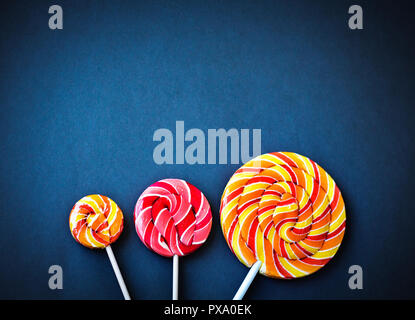 Vue du haut de trois sucettes multicolores isolé sur fond bleu foncé Banque D'Images