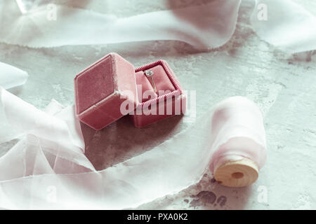 Présents : velours rose romantique fort avec une bague de mariage et des rubans de satin sur fond gris Banque D'Images