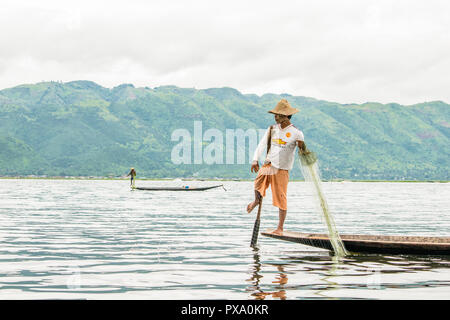Billet : local jeune pêcheur birman portant shirt Manchester United, l'équilibrage et le bateau avec son pied dans le lac Inle, Birmanie, Myanmar, en Asie Banque D'Images