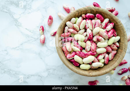Produits frais bio grains violet-beens dans bol en bois sur la table de marbre. Haricot source de protéines végétaliennes. Alimentation équilibrée, la cuisine végétarienne, et propre eati Banque D'Images