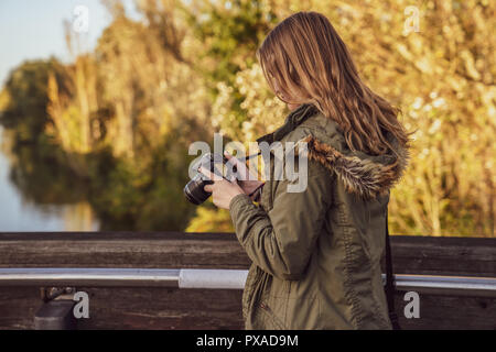 Jeune femme est debout sur un bridgewith Reflex est un contrôle photo aperçus sur l'écran de l'appareil photo Banque D'Images