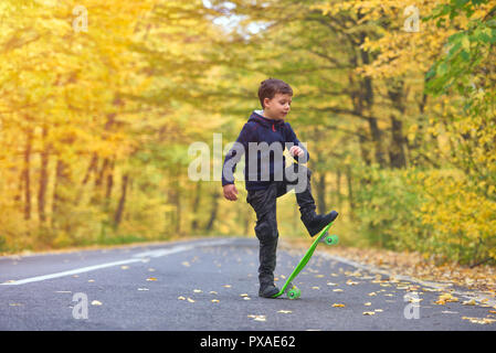 Skateboarder Kid faire skateboard tricks en environnement d'automne Banque D'Images