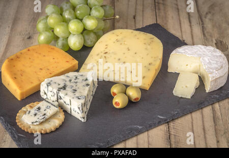 Plateau à Fromage avec quatre fromages Gouda, avec pimento, gouda avec les graines de cumin, camembert et Roquefort le fromage bleu close up sur fond de bois rustique Banque D'Images