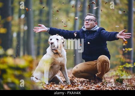 Homme avec chien dans la forêt. Propriétaire d'animal de labrador retriever bénéficiant de l'automne. Banque D'Images