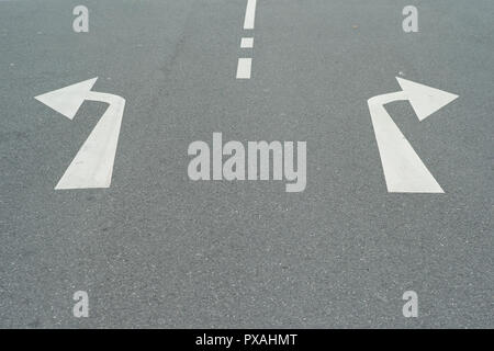 Flèches à droite et à gauche sur une route asphaltée - un concept de décisions - Tourner à gauche ou à droite Banque D'Images