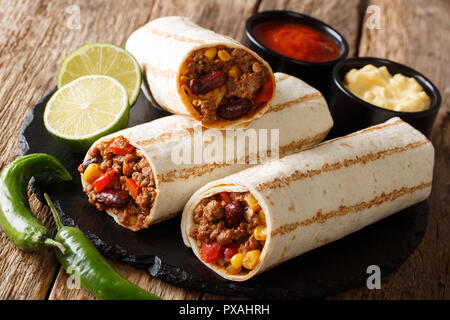 Grillé populaire mexicaine snack Burrito au boeuf et légumes et avec des sauces sur la table horizontale. Banque D'Images