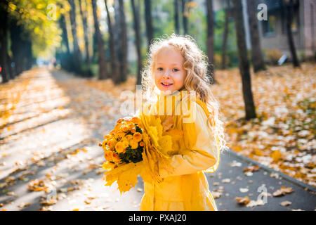 Belle petite fille aux cheveux blonds en automne fond Banque D'Images