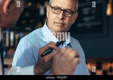 Man l'écoute de l'examen d'un collègue masculin dans le café. Business people talking sur un nouveau plan d'affaires tout en restant assis dans un restaurant. Banque D'Images