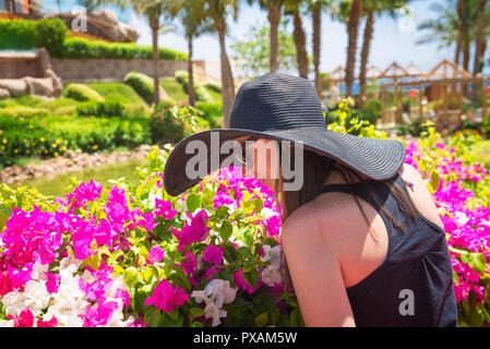 Woman smelling une fleur dans le parc Banque D'Images