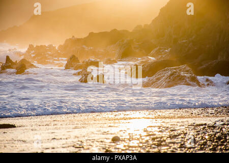 Coucher de soleil spectaculaire sur scène rocky et misty beach près de Tenby, Pembrokeshire Coast, South Wales, Uk.heure d'Or.paysage éclaboussures des vagues sur les roches crea Banque D'Images