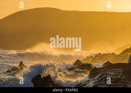 Coucher de soleil spectaculaire sur scène rocky et misty beach près de Tenby, Pembrokeshire Coast, South Wales, Uk.heure d'Or.paysage éclaboussures des vagues sur les rochers. Banque D'Images