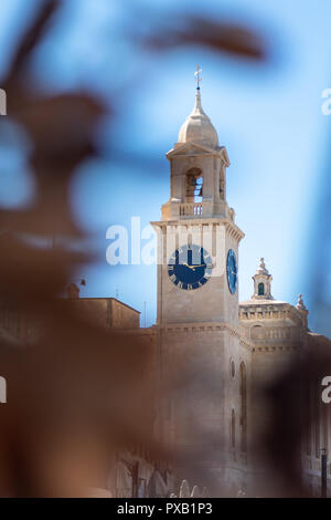 L'horloge de l'église Saint-Laurent, Birgu, Mdina, Malte entre plantes. espace pour texte. La verticale. Vue de côté. Banque D'Images