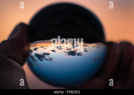 Coucher du soleil avec une différence trois personnes dans Globe au coucher du soleil à Golden bay Malte. Copiez l'espace. à l'envers. silhouette de personnes. women hand holding cryst Banque D'Images