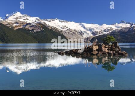 Pin Tree isolé sur Rock Island. Crêtes de montagne enneigées Garibaldi Lake Calm Water Reflections. Paysage pittoresque montagnes côtières Colombie-Britannique Canada Banque D'Images