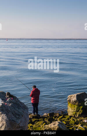 Homme dans un manteau rouge pêche le bras sud du fleuve Fraser Banque D'Images