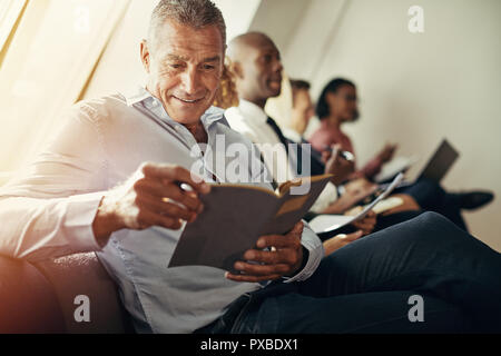 Mature businessman sitting avec les collègues pendant un office présentation lire des notes sur un ordinateur portable Banque D'Images