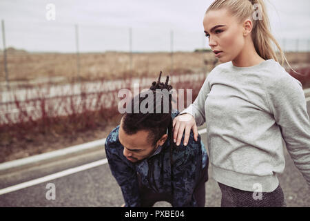 Assez jeune couple reprendre leur souffle tandis que sortir courir ensemble sur une route de campagne sur l'image Banque D'Images