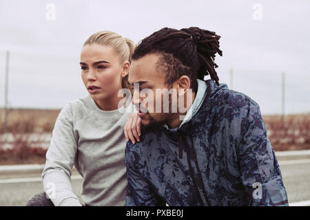 Diverses jeune couple en faisant une pause sur une route alors que sortir courir dans la campagne sur l'image Banque D'Images