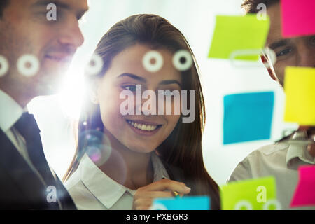 Happy girl travaille avec des collègues de bureau avec post it en premier plan. Concept d'équipe et le partenariat Banque D'Images