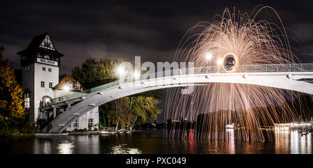 Berlin, Allemagne. 20 Oct, 2018. Un homme se tient sur le pont de l'île de la jeunesse et crée un cercle de feu dans le ciel du soir. Crédit : Paul Zinken/dpa/Alamy Live News Banque D'Images