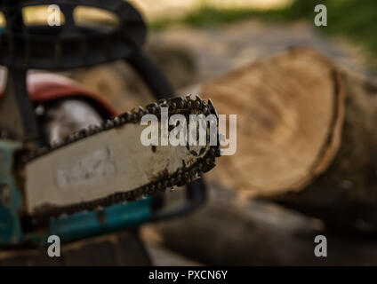 Chainsaw sur l'arrière-plan de grumes à sciages de bois de chauffage pour l'hiver. Banque D'Images