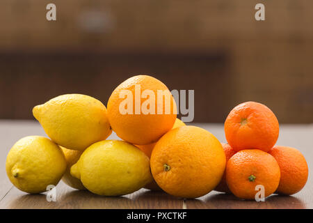Nature morte avec oranges, citrons et mandarines placés ensemble dans des groupes, sur un arrière-plan et la surface du marron Banque D'Images
