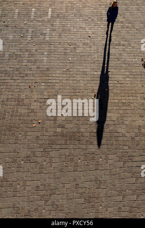 Une femme marche jette une ombre sur une longue après-midi d'automne Banque D'Images
