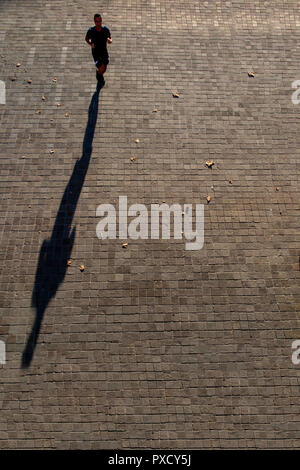 Un runner jette une ombre sur une longue après-midi d'automne Banque D'Images