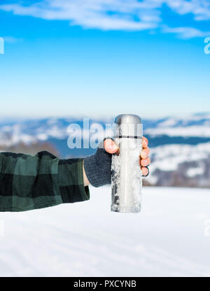 L'homme à l'aide de bouteille thermos sur la montagne enneigée Banque D'Images