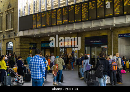 Les voyageurs debout regardant le train électronique principal panneaux dans le grand hall du King's Cross Station, London, UK Banque D'Images