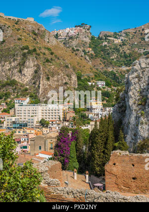 Ruines de l'ancien théâtre grec de Taormina Giardini Naxos avec village de l'arrière-plan. Province de Messine, Sicile, Italie. Banque D'Images