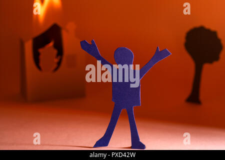 Papier coupé d'une personne contre une maison en feu. Banque D'Images