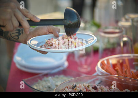 Serveur qui est à l'aide d'une louche avec salade de riz fraîchement préparés. Cuisine italienne de qualité. Une cuisine typiquement italienne. Banque D'Images