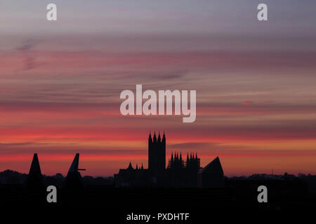 Stripey rose nuages à l'aube sur la cathédrale de Canterbury en octobre. Silhouette de la cathédrale de Canterbury et divers toits et un the maltings. Banque D'Images