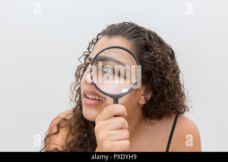 Girl looking at son sourcil les poils à l'aide d'une loupe. Concept de soins sourcils Banque D'Images