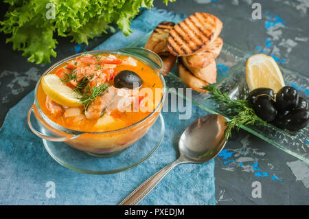 Soupe de poisson française Bouillabaisse aux fruits de mer, filet de saumon, crevettes, saveur riche, délicieux dîner dans un beau plat blanc. Banque D'Images