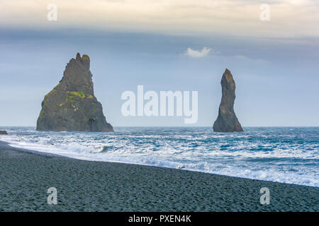 Plage de sable noir de Reynisfjara qui jouit des orgues basaltiques étonnantes formations rocheuses, une covern voûtée, et rock sea stacks visible de la plage dans le son l'Islande Banque D'Images