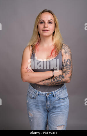 Belle jeune femme aux cheveux blonds contre l'arrière-plan gris Banque D'Images