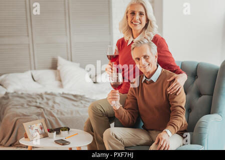 Heureux Senior couple sitting on chair and looking at camera Banque D'Images