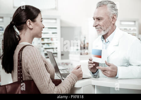 Pharmacien barbu souriant agréable recommander bonne comprimés son visiteur Banque D'Images