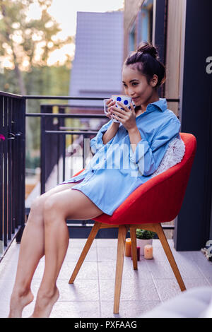 Heureux jeune femme assise sur le balcon Banque D'Images