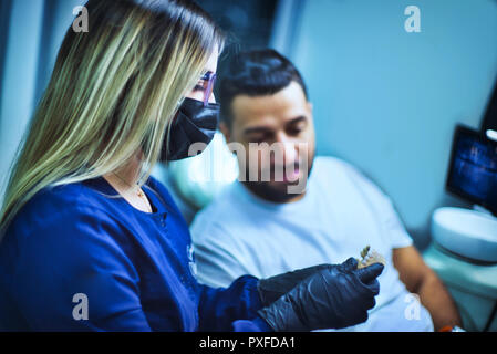 Femme médecin dentiste montre un modèle de la mâchoire et des dents au patient d'établir un diagnostic Banque D'Images