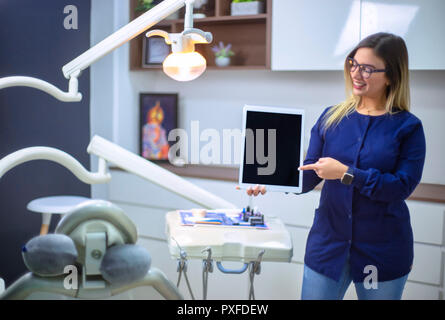 Jeune et belle dentiste tient dans sa main appareil tablette numérique moderne Banque D'Images