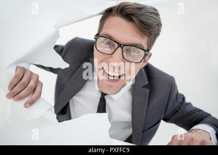Close up.mec drôle avec des lunettes à travers un trou dans le pa Banque D'Images