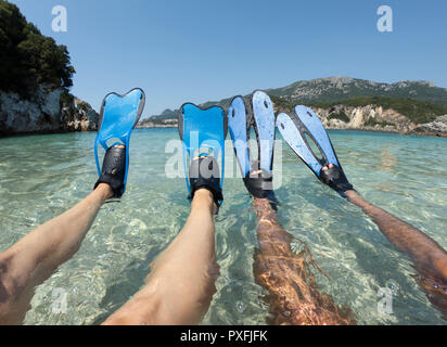 Snorkeler couple de détente sur la plage. Jambes bronzées en bleu palmes, palmes dans l'eau de mer cristalline Banque D'Images