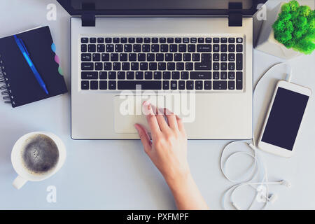 Bureau en bois gris 24 table avec un ordinateur portable, Smartphone, ordinateur portable, stylo et tasse de café. Les mains à l'aide d'un ordinateur portable et tenant une tasse de café Banque D'Images