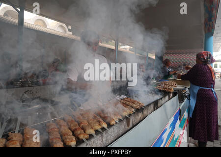 Un vendeur de viande sur le barbecue Brochettes dans un marché alimentaire à côté de bazar Chorsu situé dans le centre de la vieille ville de Tachkent, capitale de l'Ouzbékistan Banque D'Images
